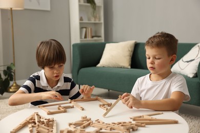 Photo of Cute brothers playing with wooden construction set at table indoors