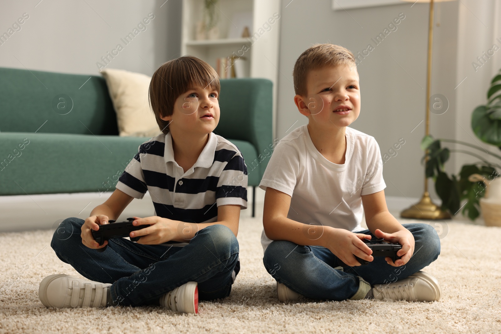 Photo of Cute brothers playing video game on floor at home