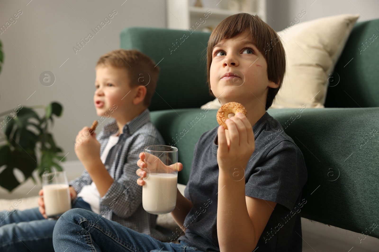 Photo of Cute brothers with glasses of milk and cookies at home, selective focus