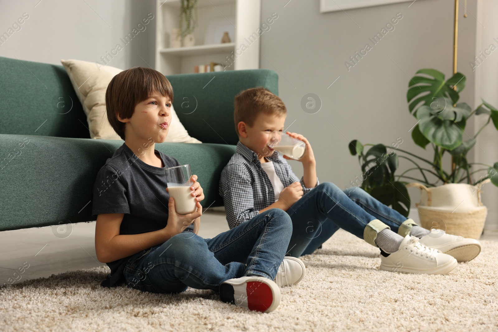 Photo of Cute brothers drinking milk on floor at home