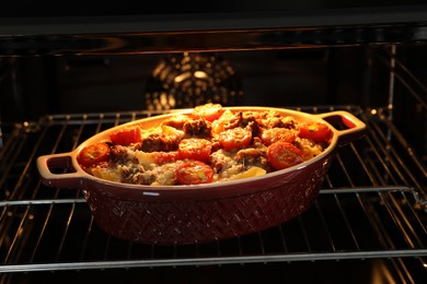 Photo of Delicious pasta casserole with cheese, tomatoes and minced meat in baking dish in oven, closeup