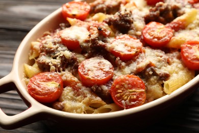 Photo of Delicious pasta casserole with cheese, tomatoes and minced meat in baking dish on wooden table, closeup