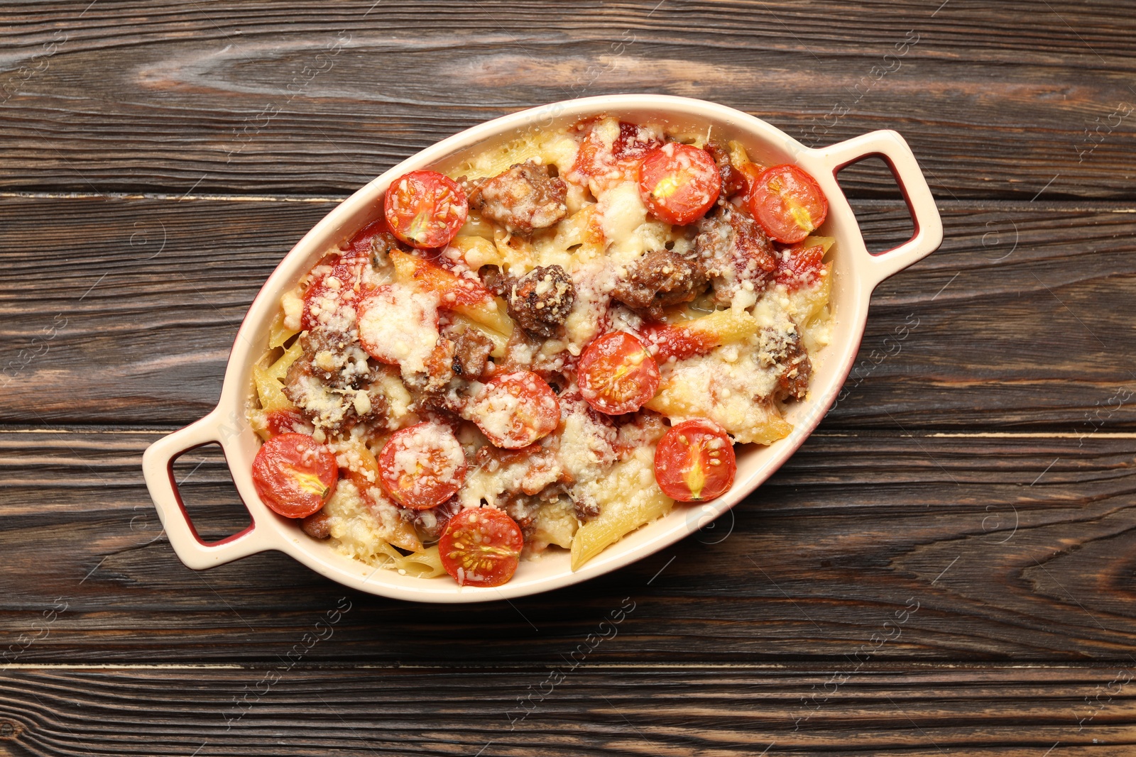 Photo of Delicious pasta casserole with cheese, tomatoes and minced meat in baking dish on wooden table, top view