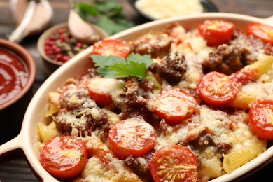 Photo of Delicious pasta casserole with cheese, tomatoes and minced meat in baking dish on table, closeup