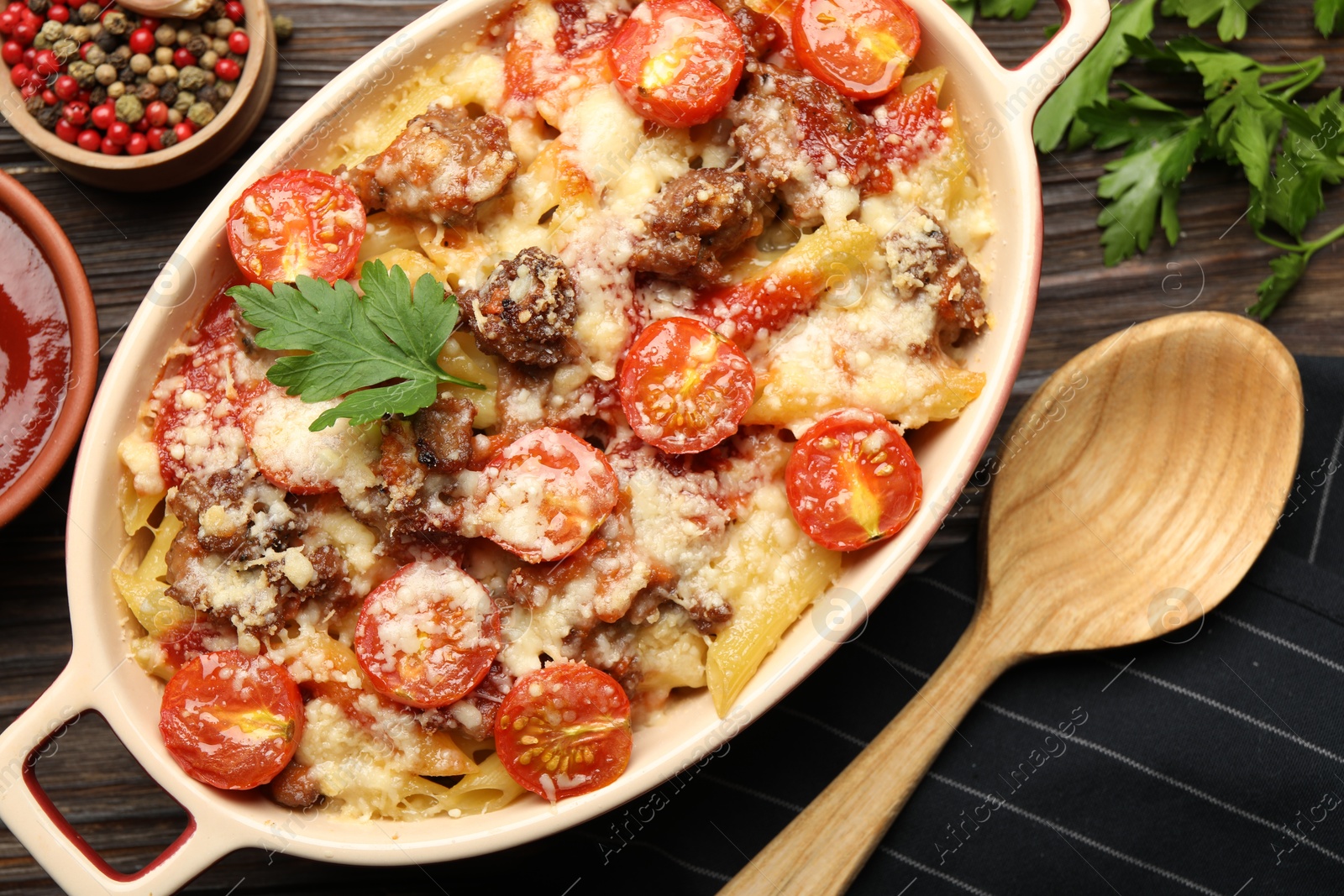 Photo of Delicious pasta casserole with cheese, tomatoes and minced meat in baking dish served on wooden table, flat lay