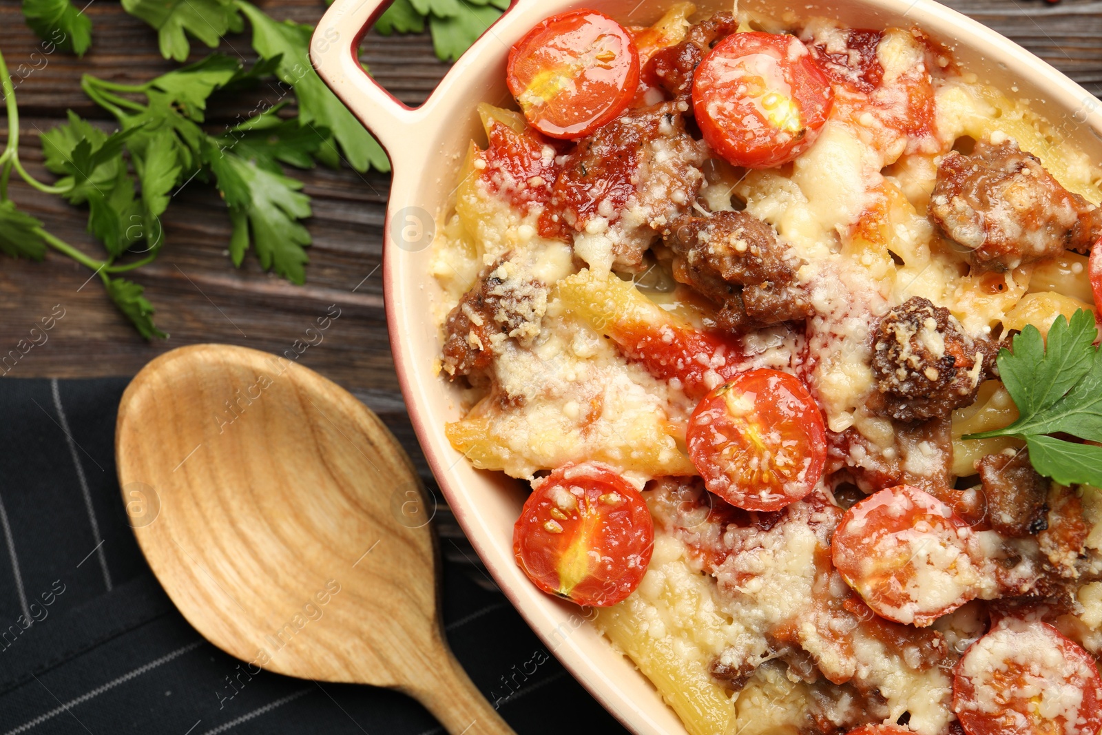 Photo of Delicious pasta casserole with cheese, tomatoes and minced meat in baking dish served on wooden table, flat lay