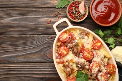 Photo of Delicious pasta casserole in baking dish with ingredients and sauce on wooden table, flat lay. Space for text