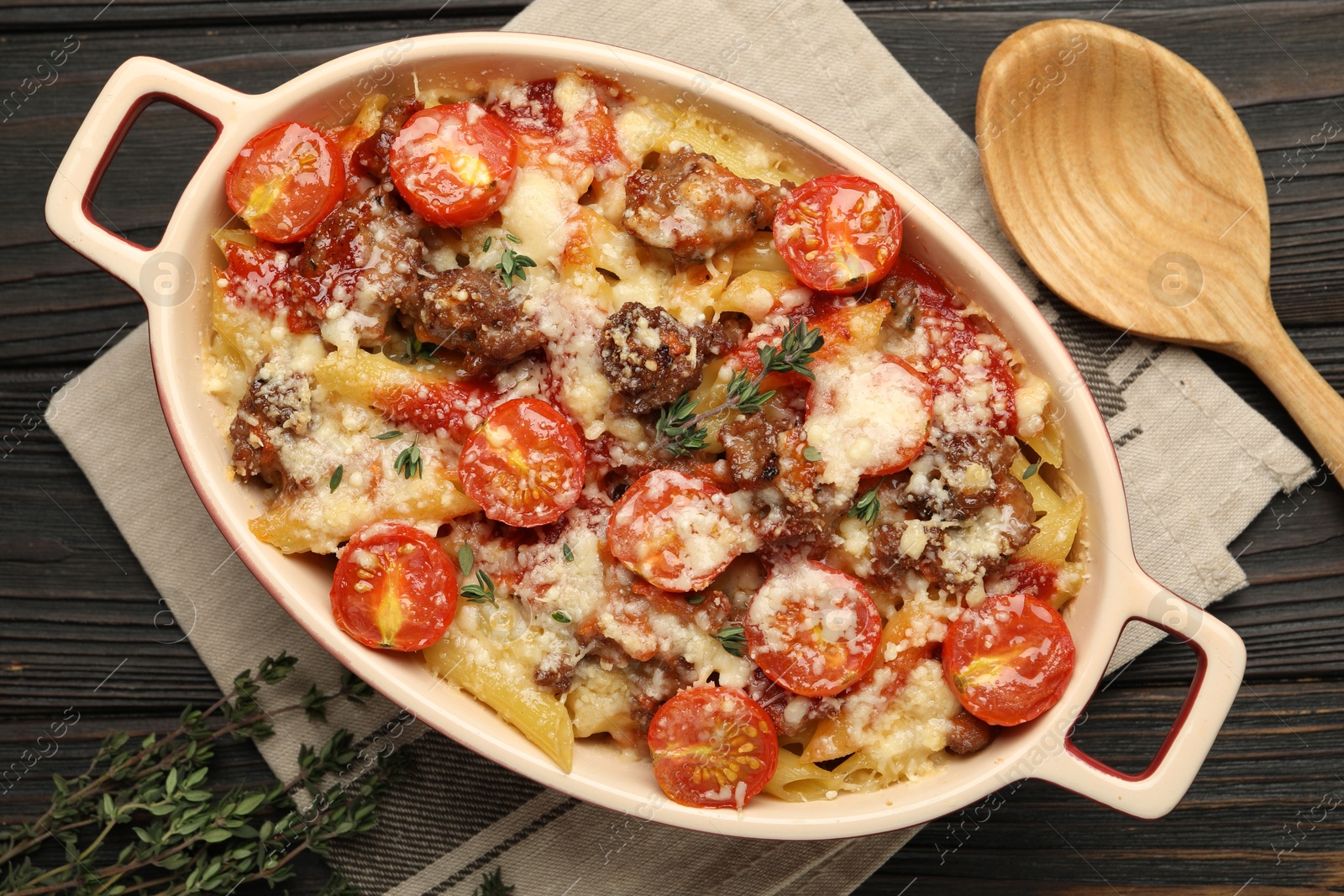 Photo of Delicious pasta casserole with cheese, tomatoes, minced meat and thyme in baking dish on wooden table, flat lay