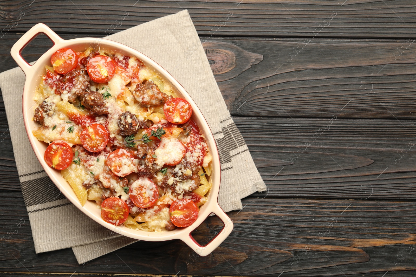 Photo of Delicious pasta casserole with cheese, tomatoes, minced meat and thyme in baking dish on wooden table, top view. Space for text