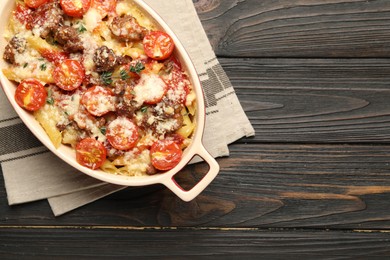 Photo of Delicious pasta casserole with cheese, tomatoes, minced meat and thyme in baking dish on wooden table, top view. Space for text