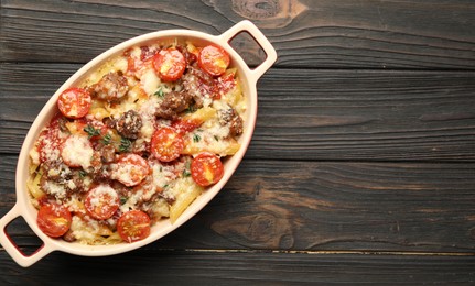 Photo of Delicious pasta casserole with cheese, tomatoes, minced meat and thyme in baking dish on wooden table, top view. Space for text