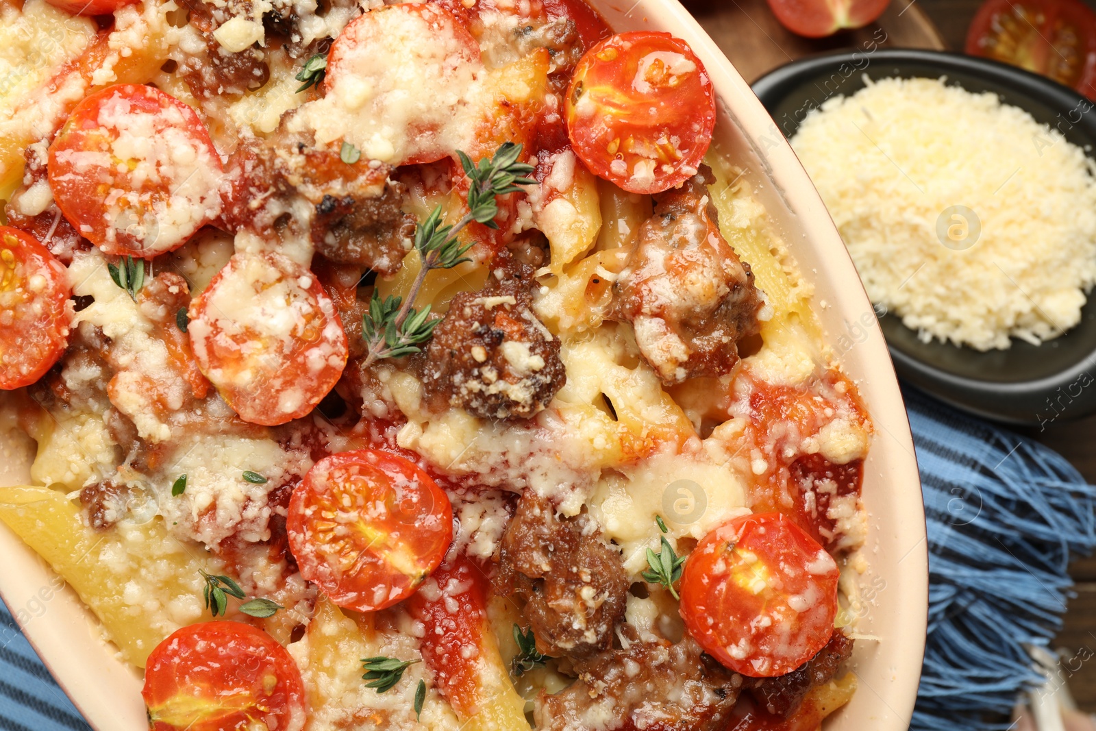 Photo of Delicious pasta casserole with cheese, tomatoes, minced meat and thyme in baking dish on table, flat lay