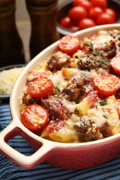 Photo of Delicious pasta casserole with cheese, tomatoes, minced meat and thyme in baking dish on table, closeup