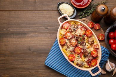 Photo of Delicious pasta casserole in baking dish with ingredients on wooden table, flat lay. Space for text