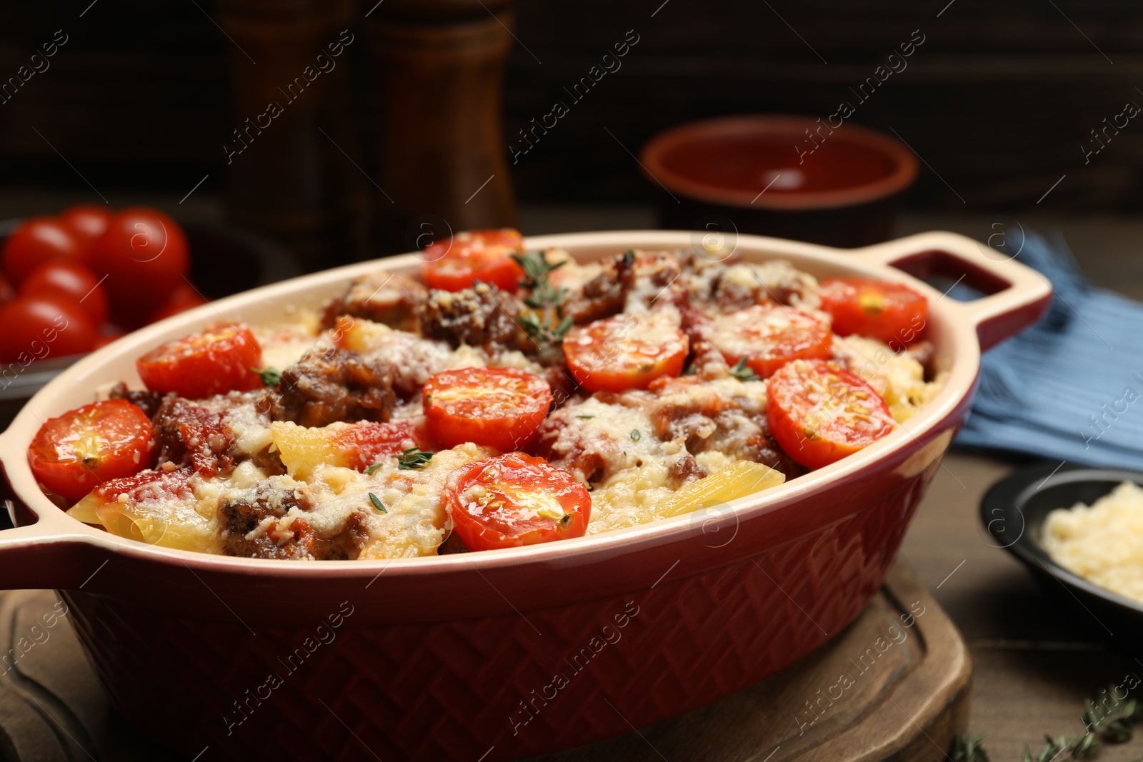 Photo of Delicious pasta casserole with cheese, tomatoes, minced meat and thyme in baking dish on table, closeup