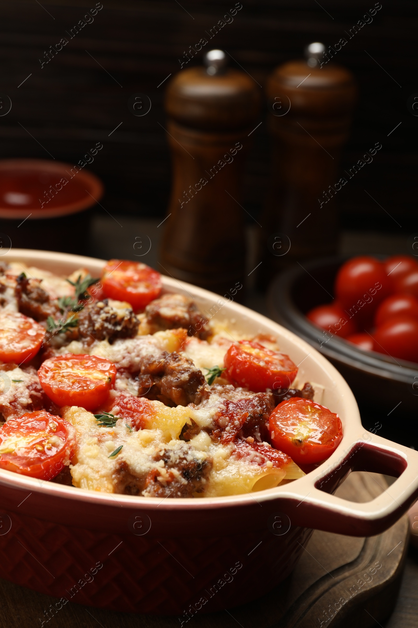 Photo of Delicious pasta casserole with cheese, tomatoes, minced meat and thyme in baking dish on table, closeup