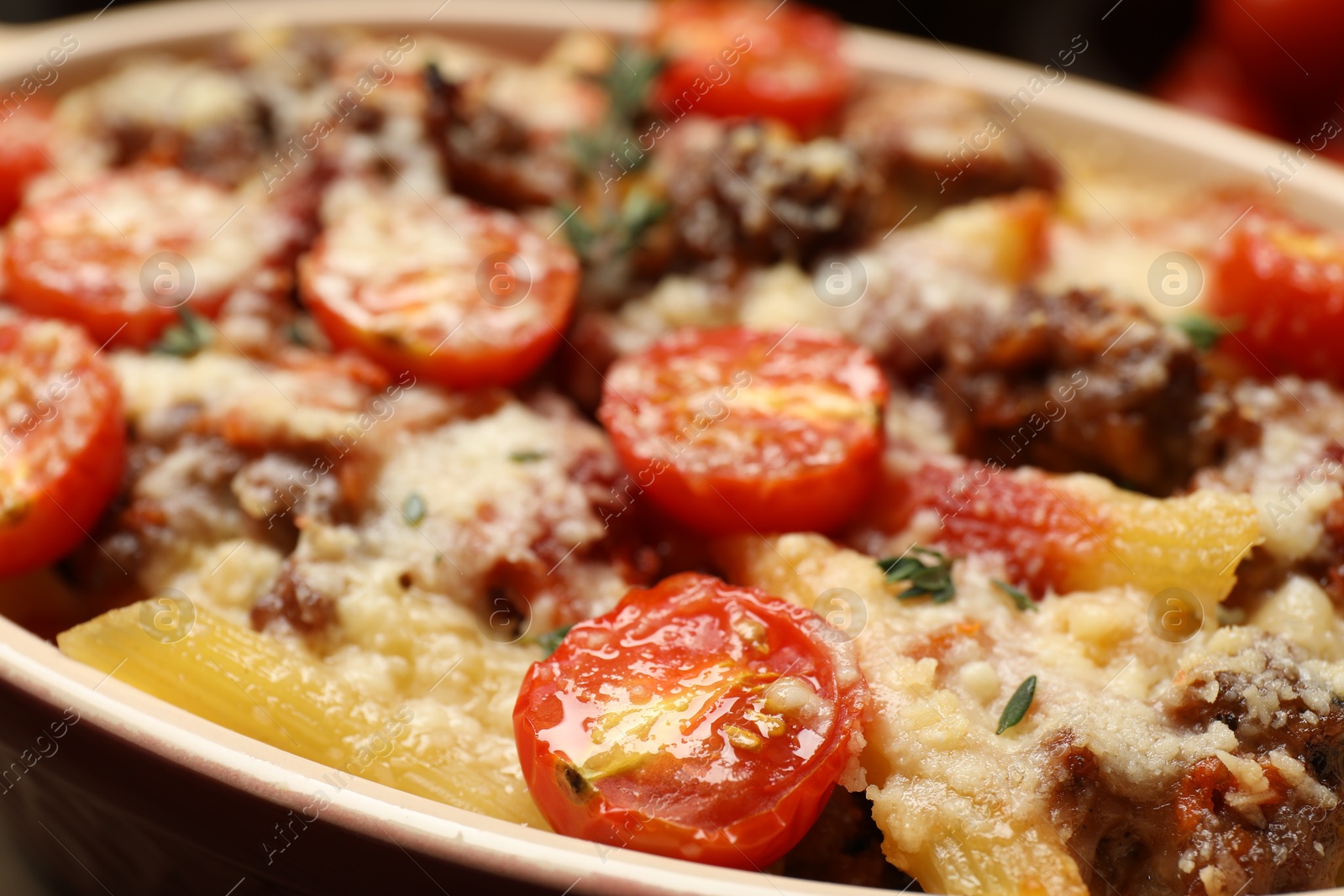 Photo of Delicious pasta casserole with cheese, tomatoes, minced meat and thyme in baking dish, closeup