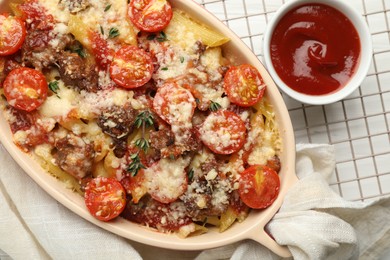 Photo of Delicious pasta casserole with cheese, tomatoes, minced meat and ketchup on white table, flat lay