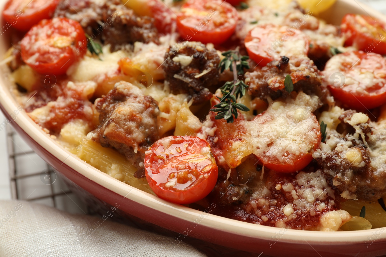 Photo of Delicious pasta casserole with cheese, tomatoes, minced meat and thyme in baking dish on table, closeup