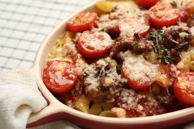 Photo of Delicious pasta casserole with cheese, tomatoes, minced meat and thyme in baking dish on white table, closeup