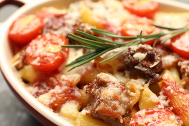 Photo of Delicious pasta casserole with cheese, tomatoes, minced meat and rosemary in baking dish, closeup