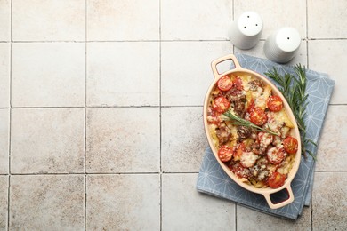 Photo of Delicious pasta casserole in baking dish, rosemary and spices on tiled table, flat lay. Space for text