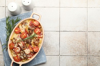 Photo of Delicious pasta casserole in baking dish, rosemary and spices on tiled table, flat lay. Space for text