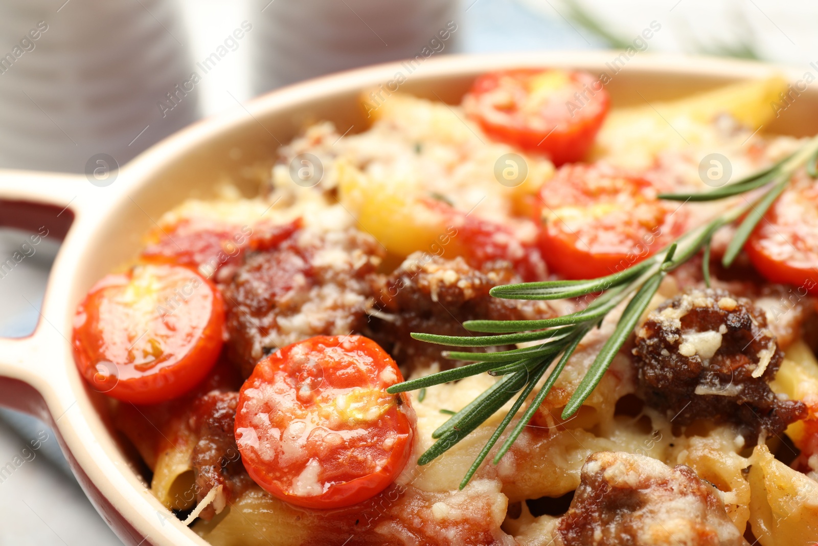 Photo of Delicious pasta casserole with cheese, tomatoes, minced meat and rosemary in baking dish, closeup