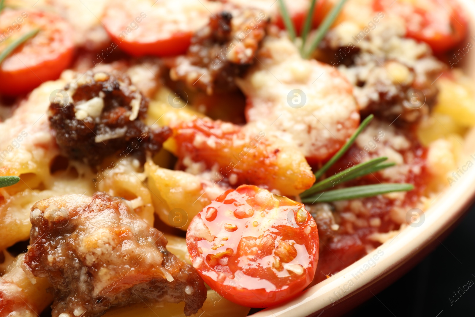 Photo of Delicious pasta casserole with cheese, tomatoes, minced meat and rosemary in baking dish, closeup