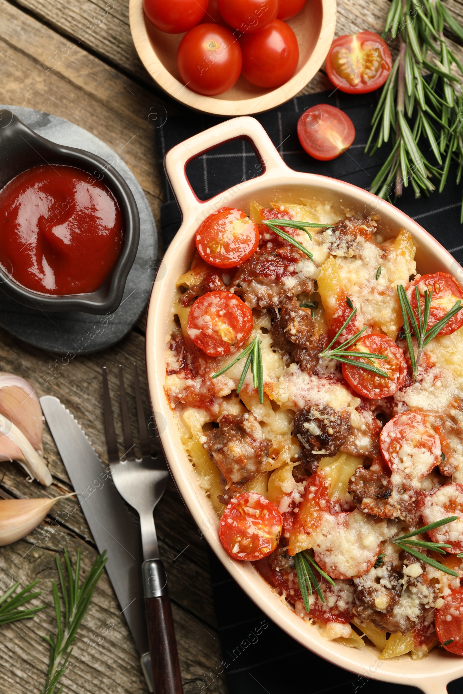 Photo of Flat lay composition with delicious pasta casserole in baking dish and ingredients on wooden table