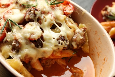 Photo of Delicious pasta casserole with cheese, tomatoes, minced meat and rosemary in baking dish, closeup