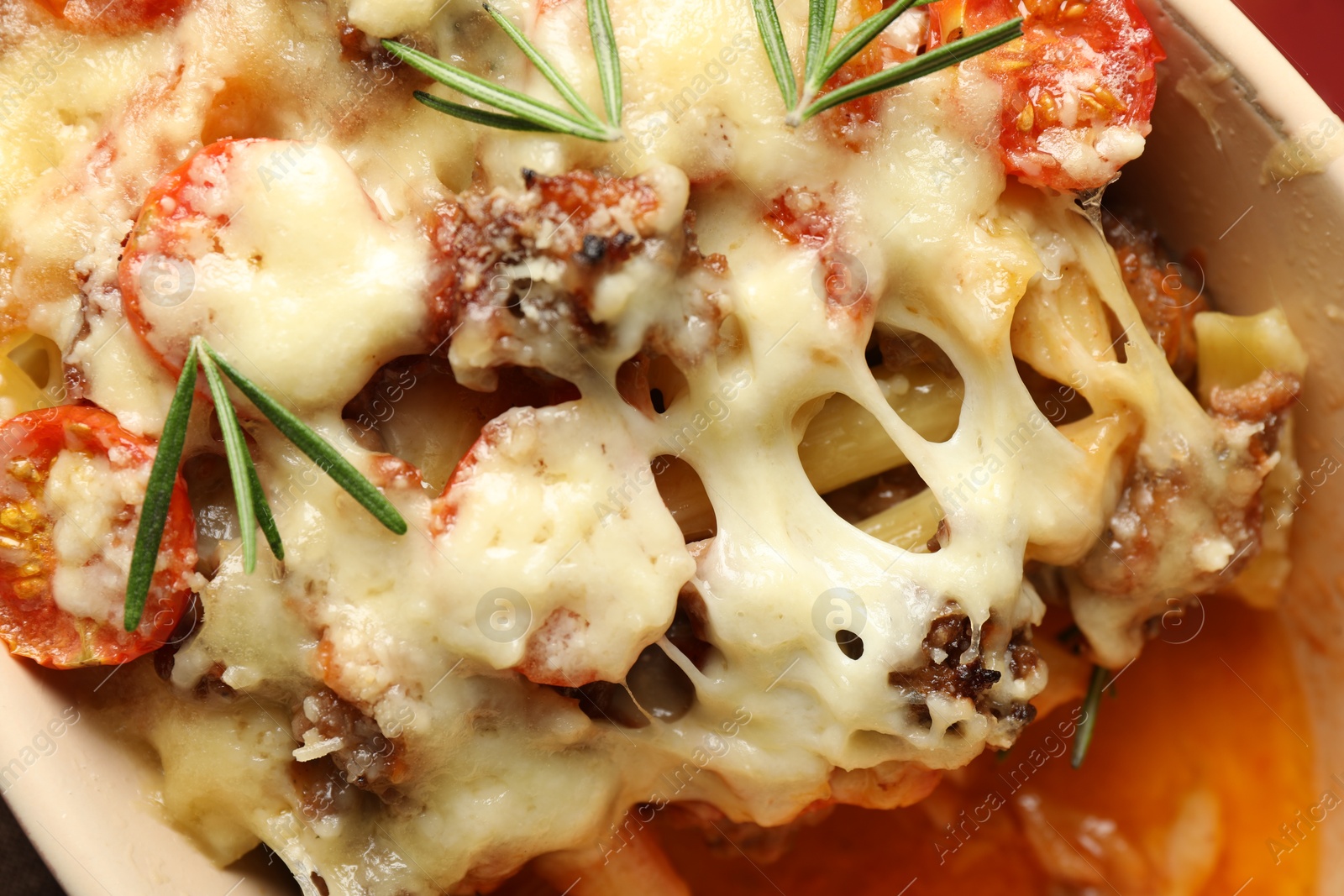 Photo of Delicious pasta casserole with cheese, tomatoes, minced meat and rosemary in baking dish, top view