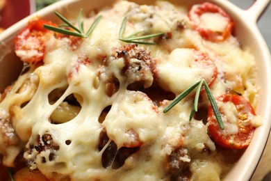 Photo of Delicious pasta casserole with cheese, tomatoes, minced meat and rosemary in baking dish, closeup