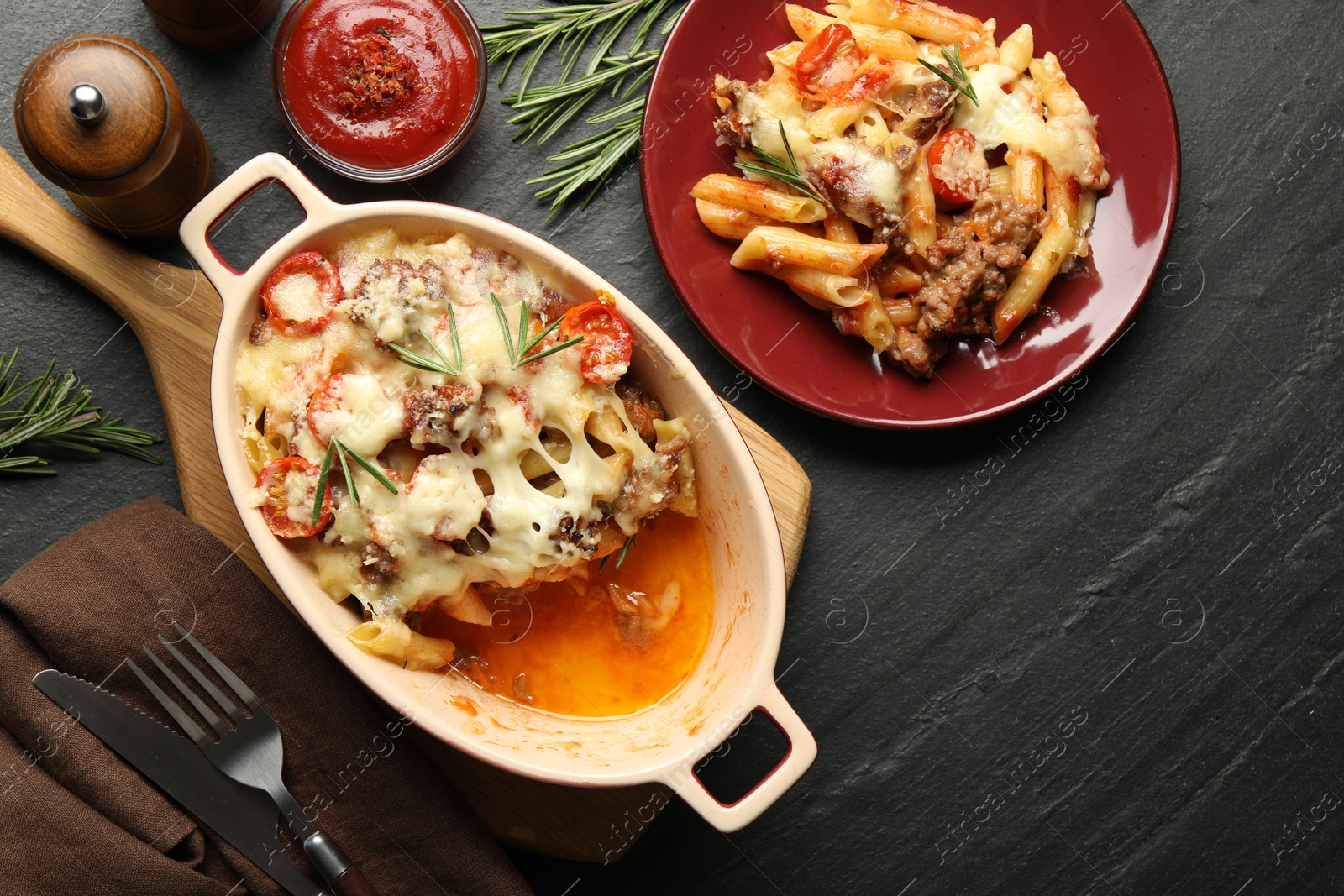 Photo of Flat lay composition with delicious pasta casserole on dark textured table