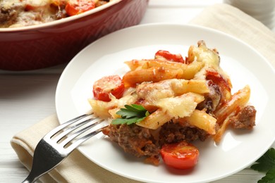 Photo of Delicious pasta casserole with cheese, tomatoes, minced meat and parsley on white wooden table, closeup