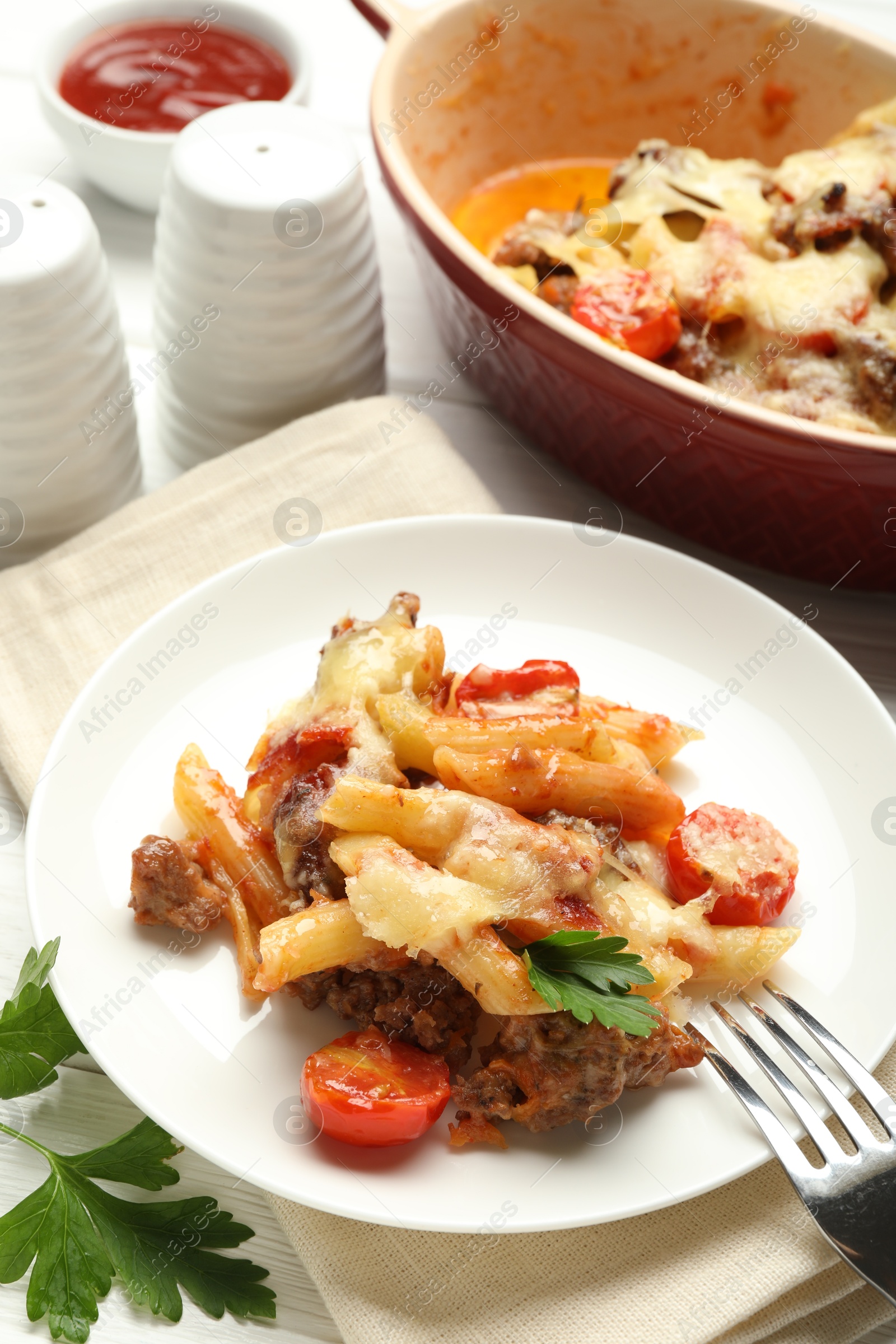 Photo of Delicious pasta casserole with cheese, tomatoes, minced meat and parsley on white wooden table