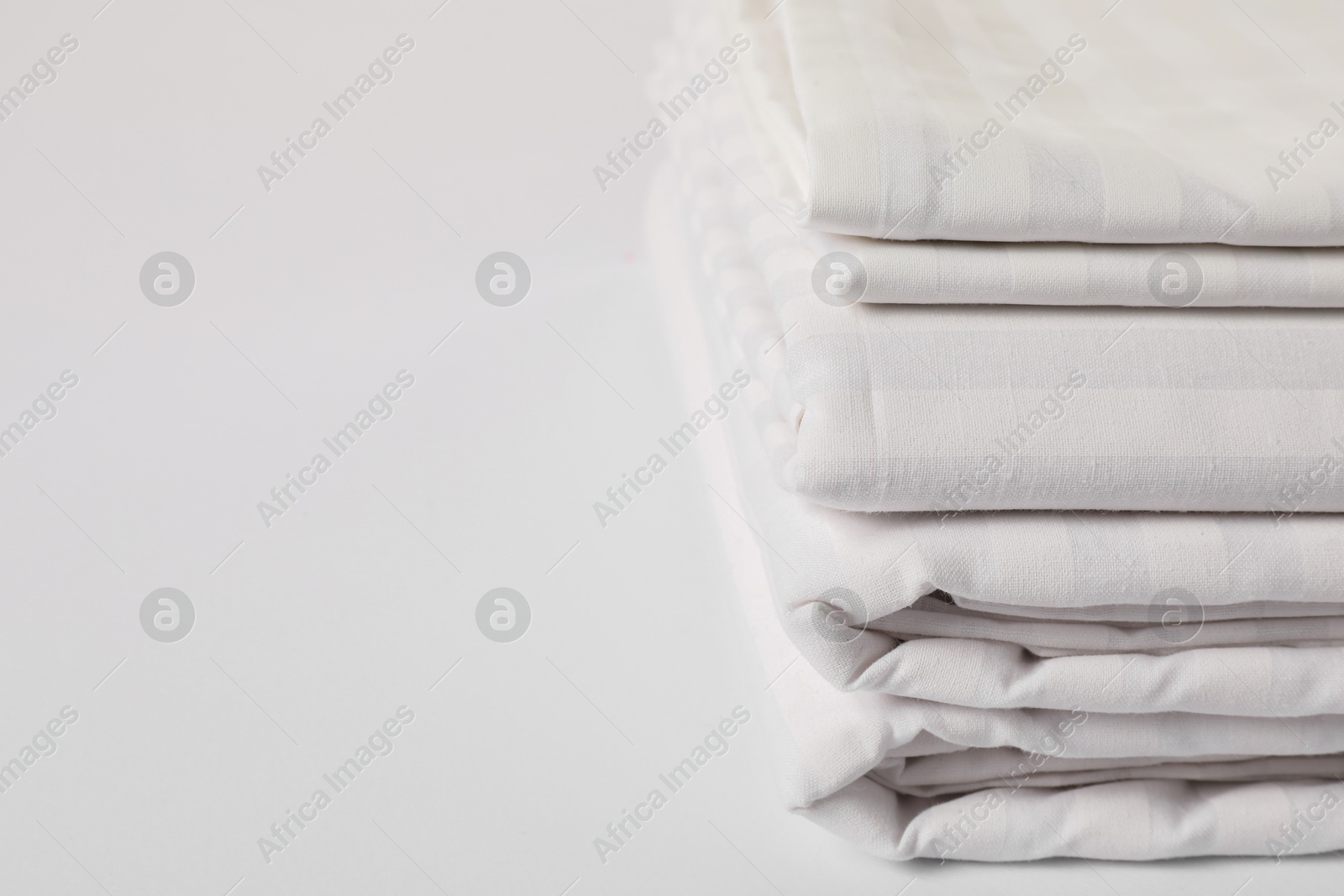 Photo of Stacked clean bed linens on white background