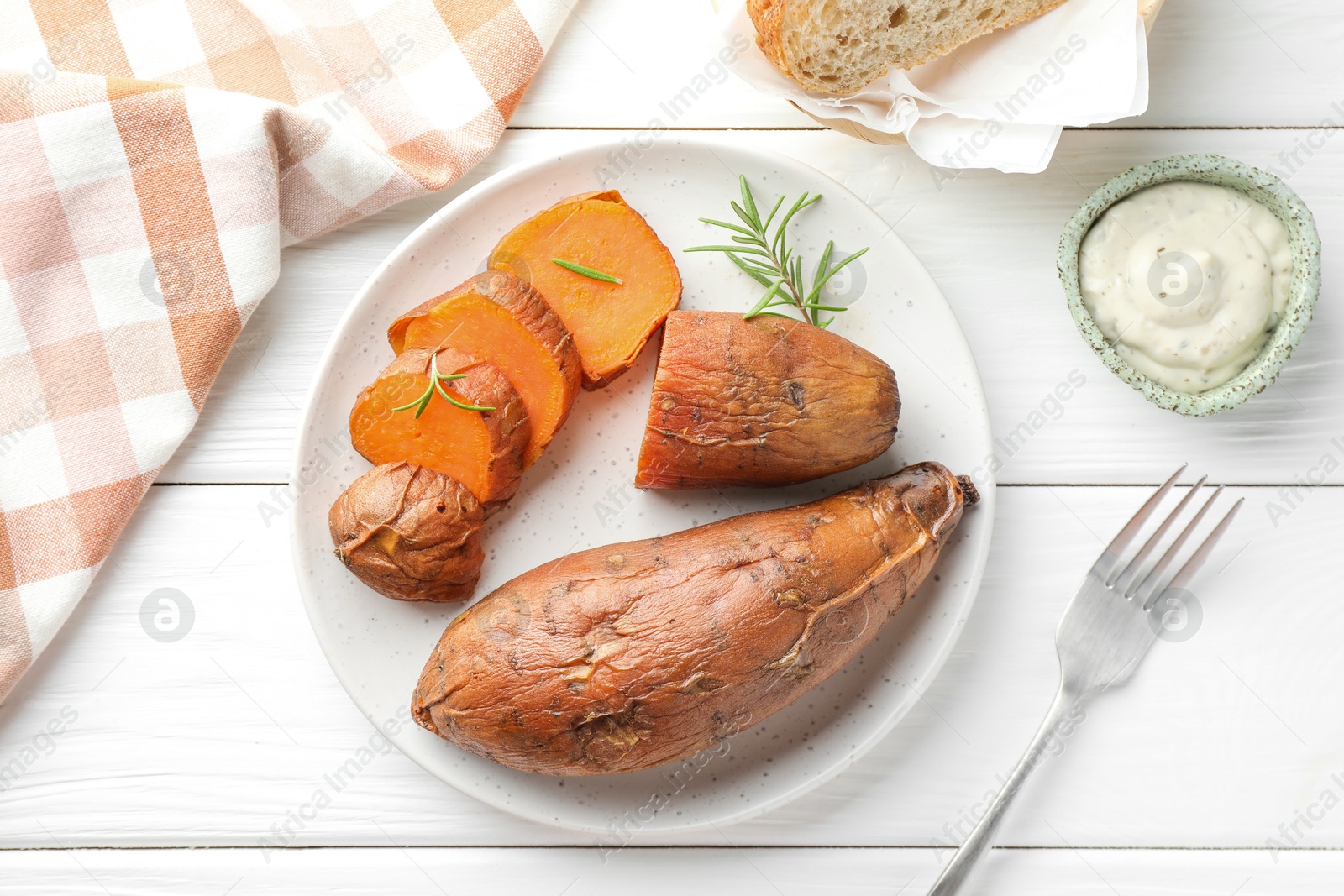 Photo of Tasty cooked sweet potatoes served with rosemary and sauce on white wooden table, top view