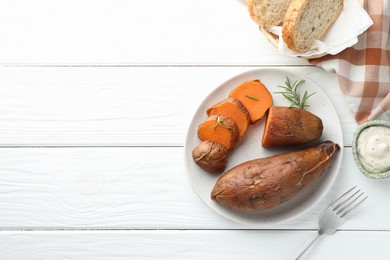 Photo of Tasty cooked sweet potatoes served with rosemary and sauce on white wooden table, top view. Space for text