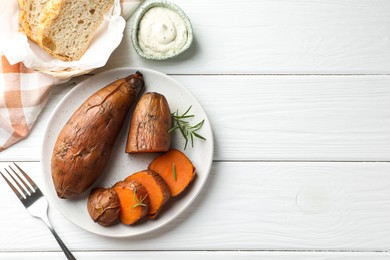 Photo of Tasty cooked sweet potatoes served with rosemary and sauce on white wooden table, top view. Space for text