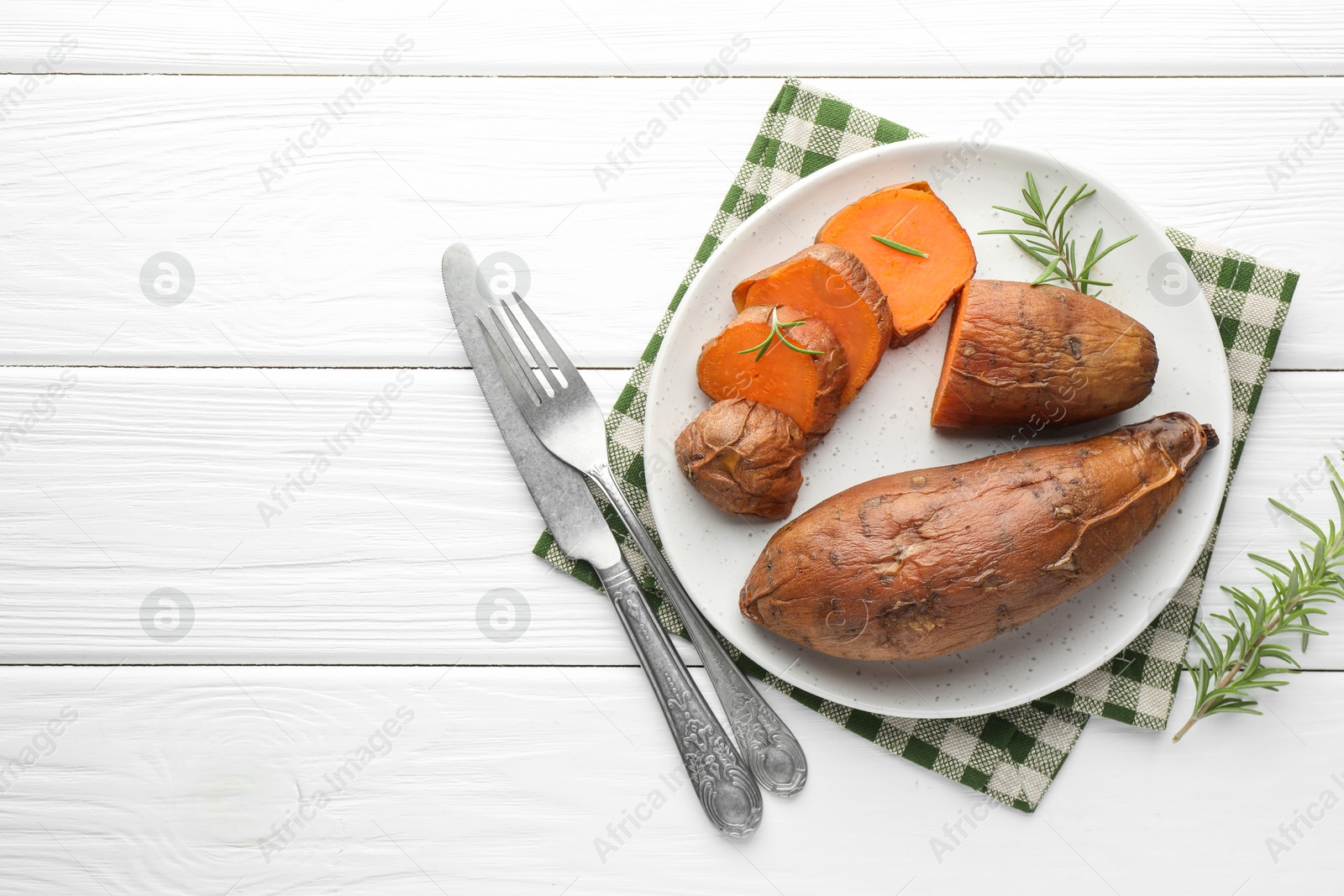 Photo of Tasty cooked sweet potatoes served with rosemary on white wooden table, top view. Space for text