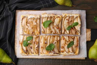 Photo of Tasty puff pastry pie with pears and mint on wooden table, top view