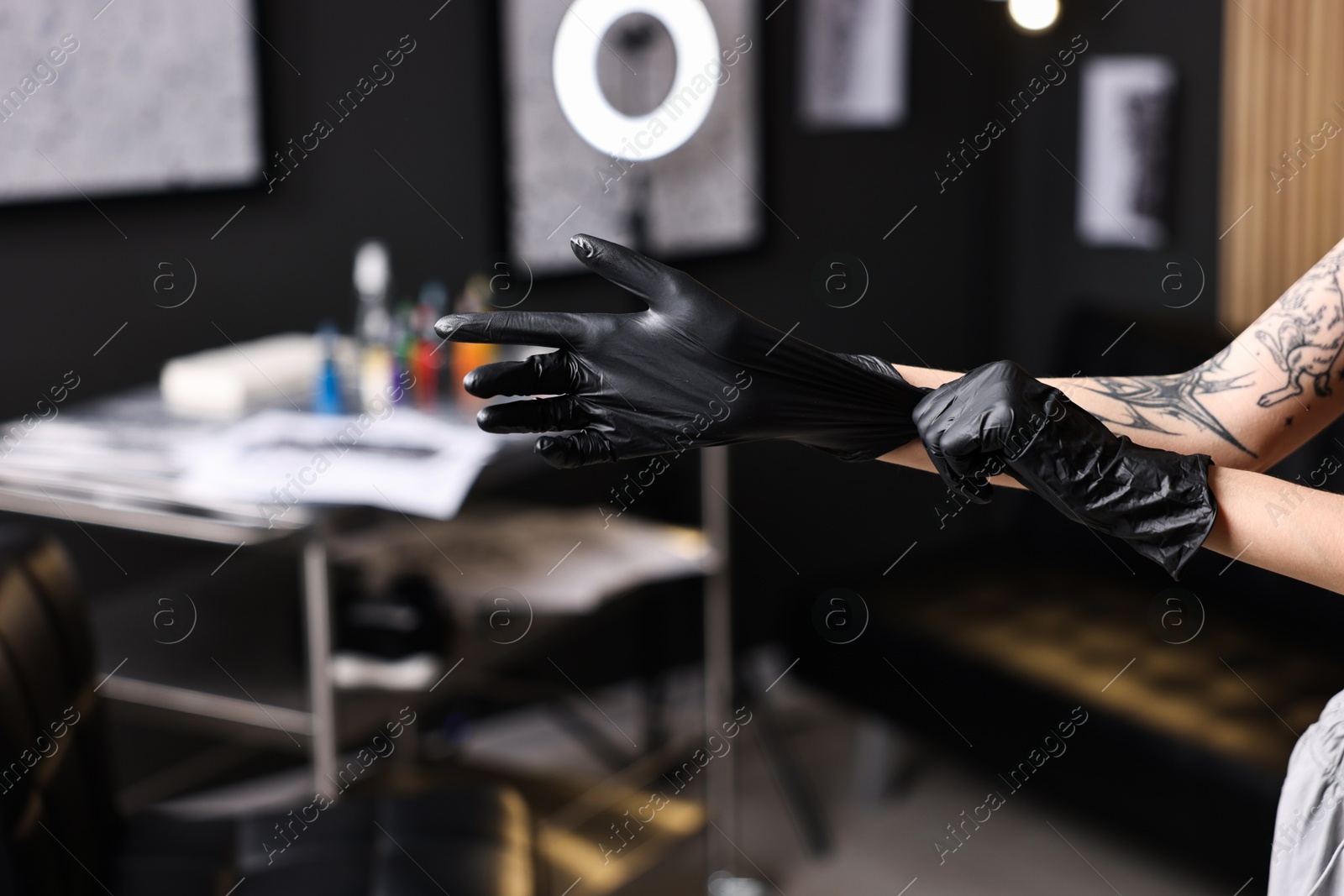 Photo of Professional tattoo artist wearing gloves in salon, closeup. Space for text