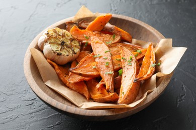 Tasty cooked sweet potatoes with parsley and garlic on black table, closeup