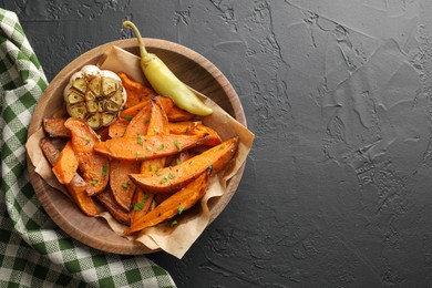 Photo of Tasty cooked sweet potatoes with garlic and pickled pepper on black table, top view. Space for text