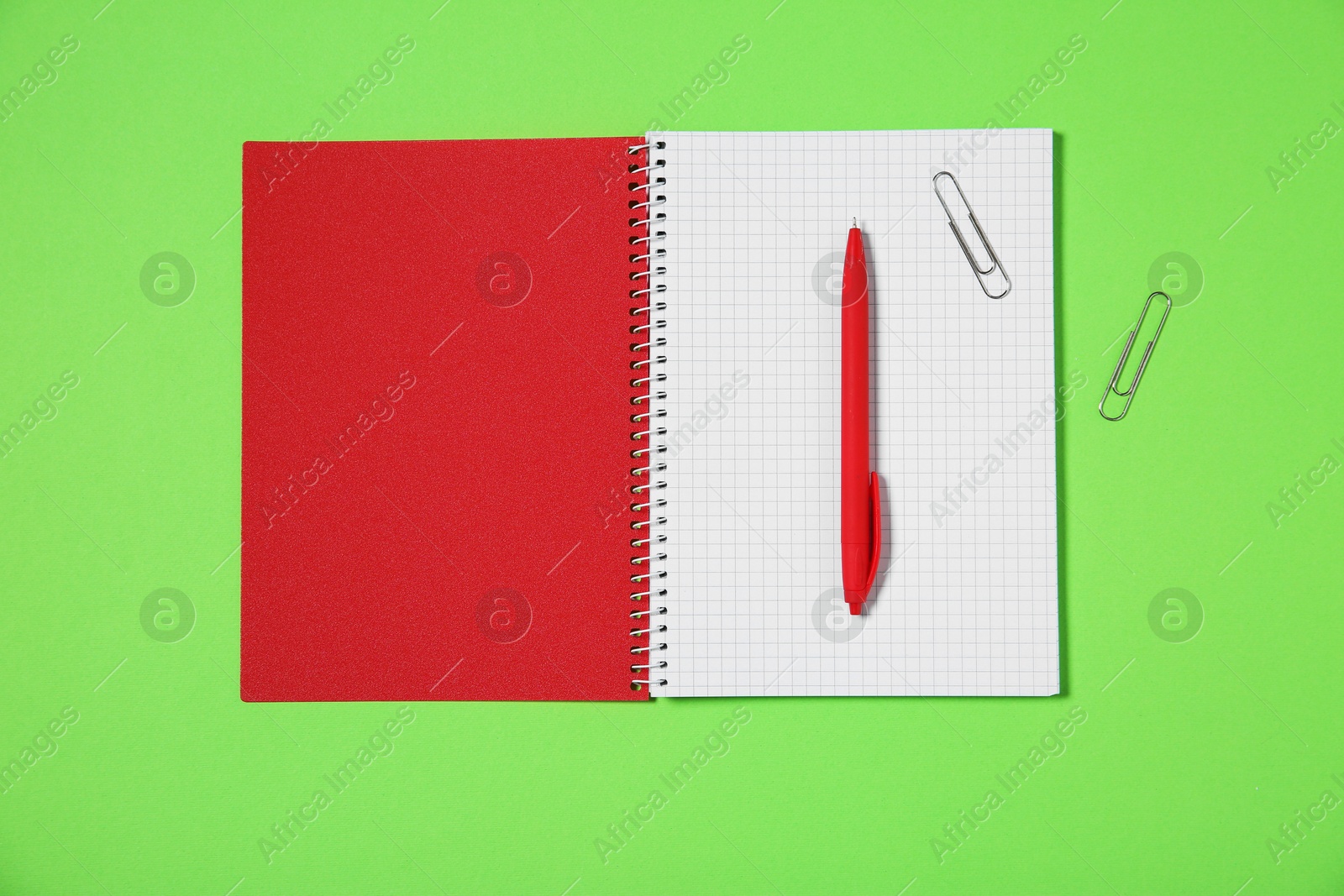 Photo of Notebook, paper clips and pen on light green background, top view