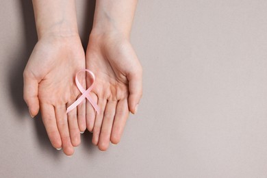 Photo of Woman with pink ribbon on grey background, top view and space for text. Breast cancer awareness