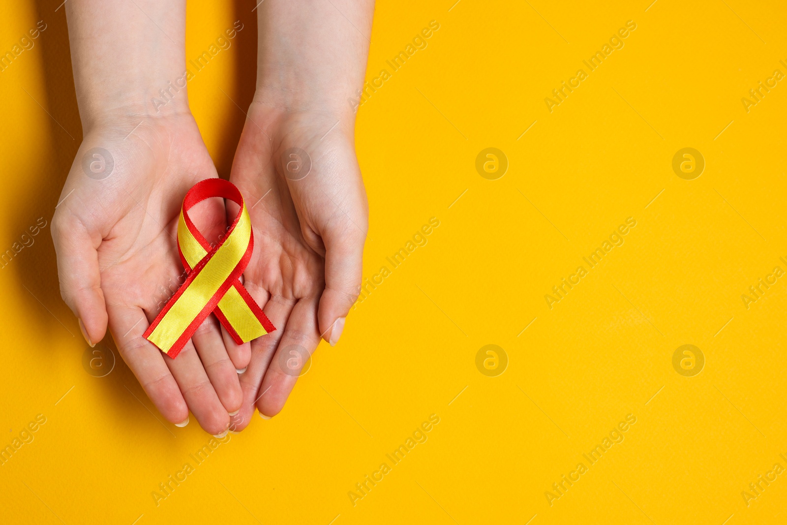 Photo of Woman with colorful ribbon on yellow background, top view and space for text. Hepatitis C awareness