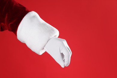 Photo of Santa Claus holding something on red background, closeup. Space for text