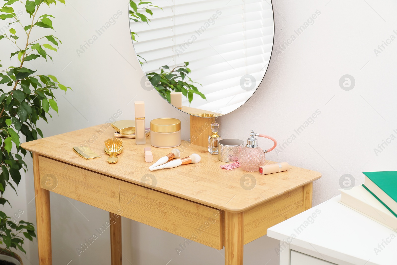 Photo of Mirror, dressing table with cosmetic products and houseplant indoors. Interior design